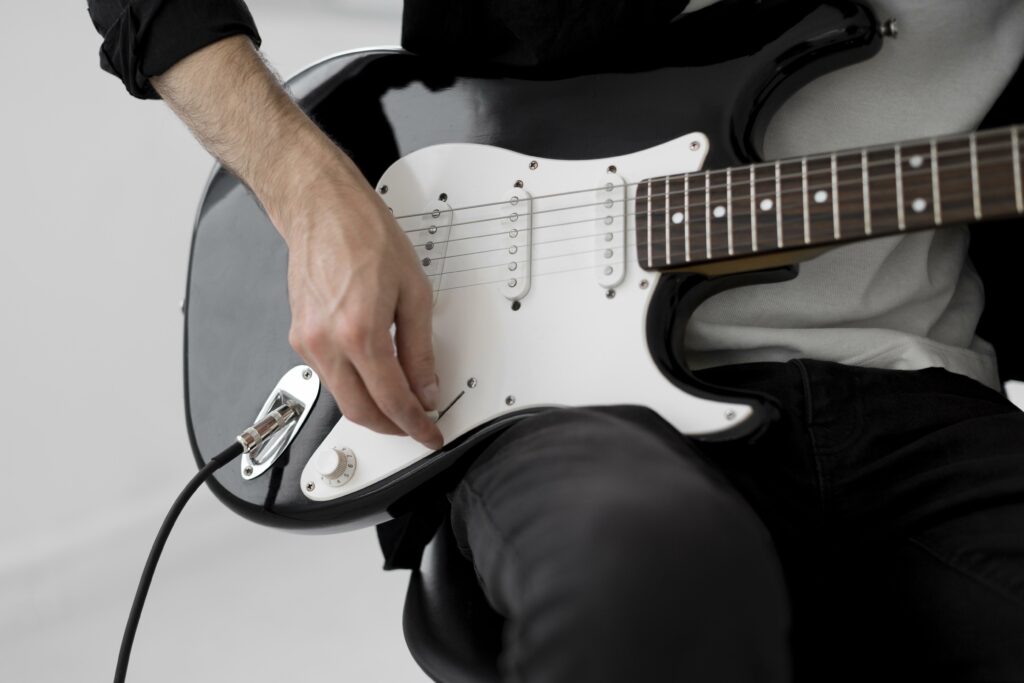 Homem tocando uma guitarra Stratocaster preta com detalhe branco